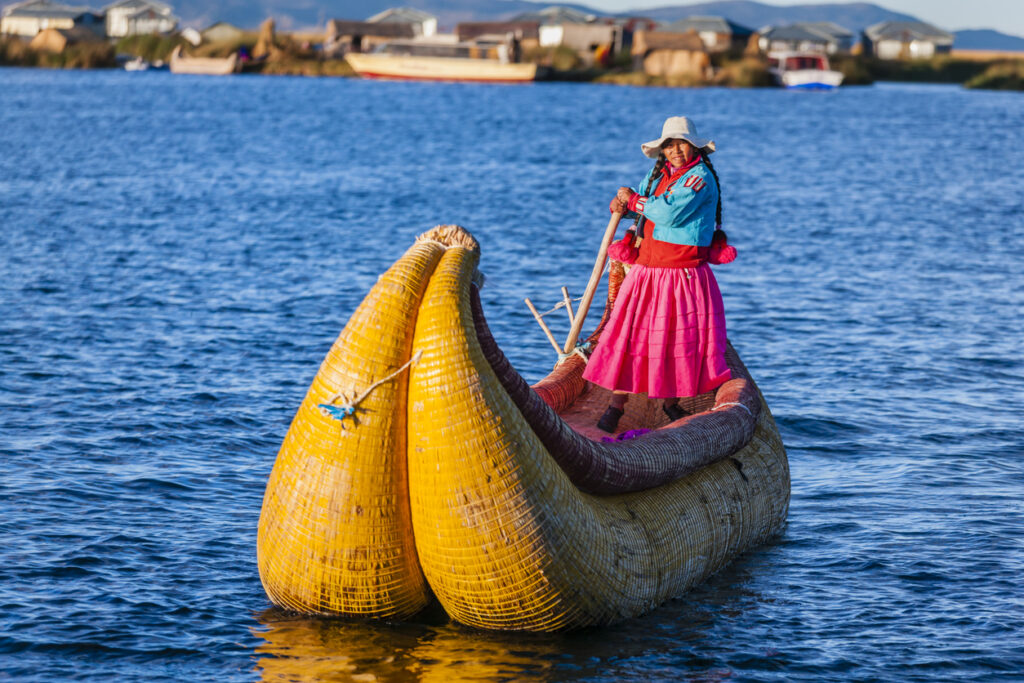 Peruvian woman sailing between Uros floating islands, Lake Tititcaca